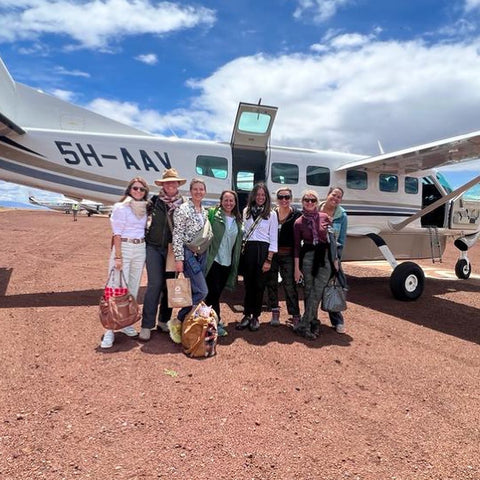 A group of woman standing in front of plane in Africa ready to go on safari in Tanzania